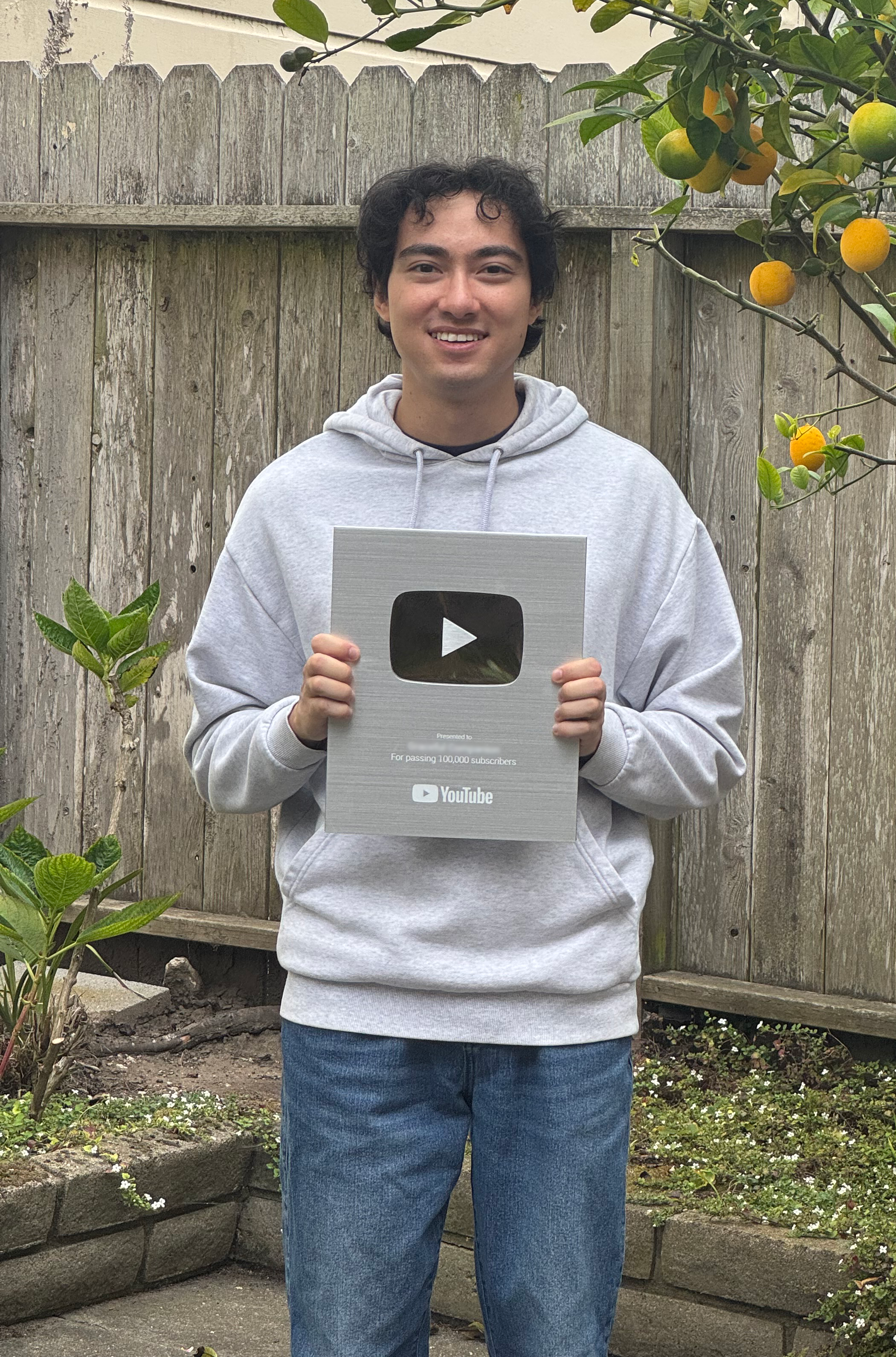 Benjamin Hadler holding a silver YouTube play button outdoors